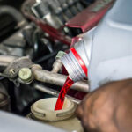 A man pours Amsoil Synthetic Oil into an engine