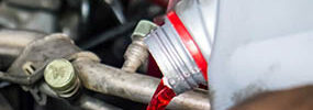 A man pours Amsoil Synthetic Oil into an engine