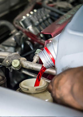 A man pours Amsoil Synthetic Oil into an engine